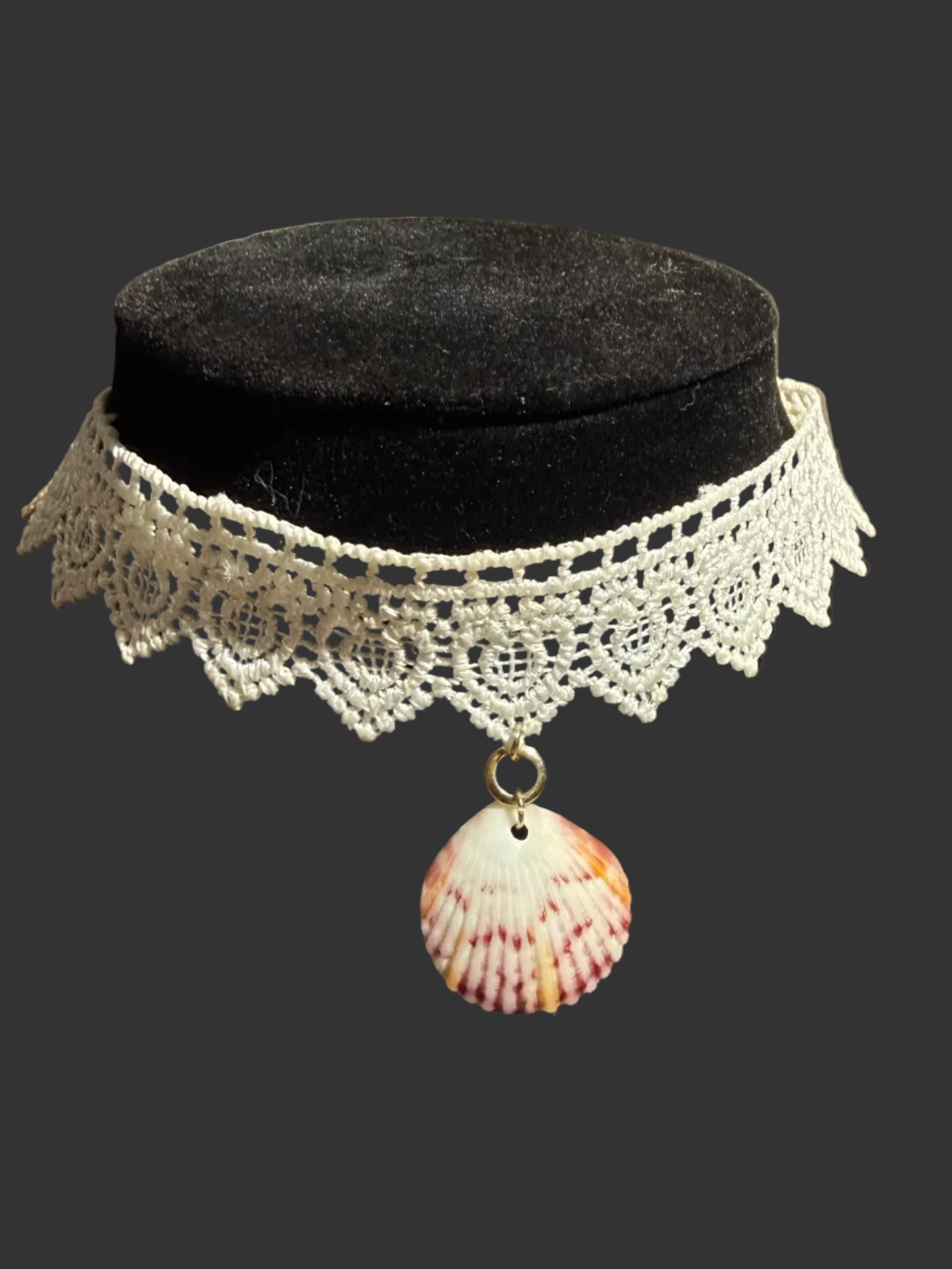 A white crocheted lace choker necklace with a pink and white seashell pendant, displayed on a black velvet jewelry bust.